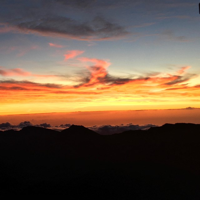 a dimmed horizon with pink and orange colors reflecting on the clouds
