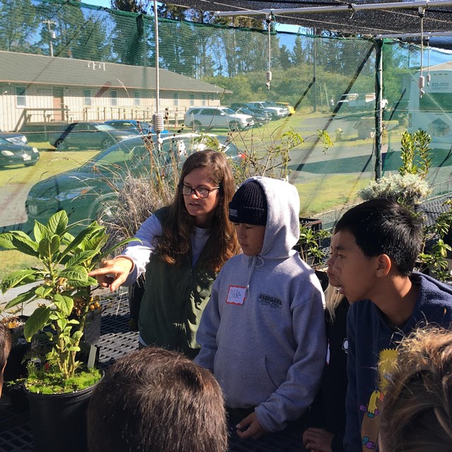 A ranger leads students in the greenhouse