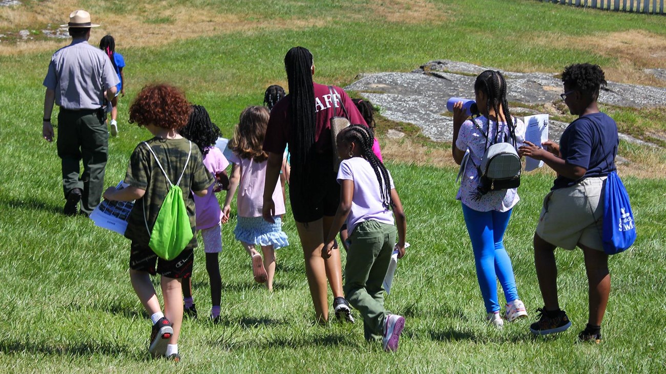 A group of young people running towards the overseer's house. They are following a park ranger.
