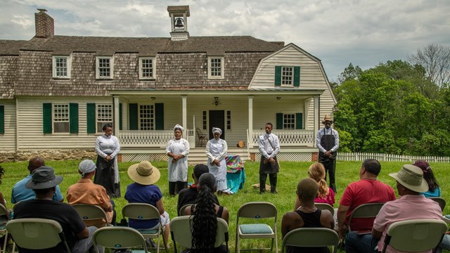 A Juneteenth program being help in front of the farm house on the farm side of Hampton NHS.
