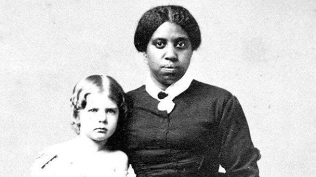 A black and white photo of an enslaved person with a white child.