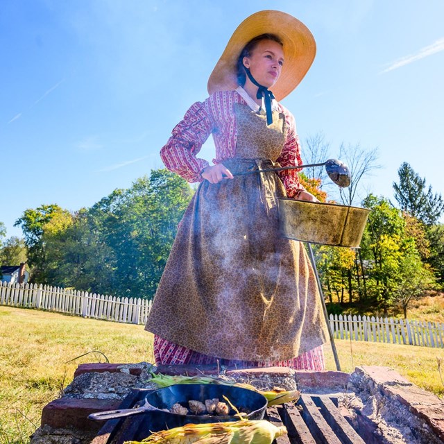 A living historian demonstrating outdoor cooking