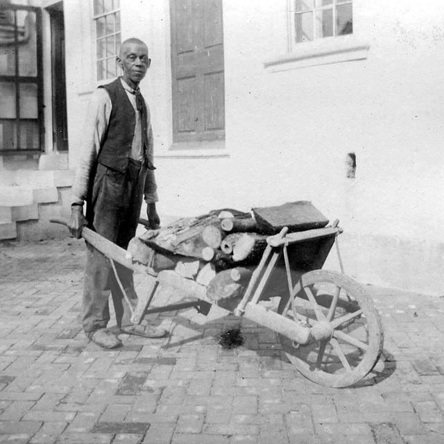African American man holding a wheelbarrow outside of the mansion