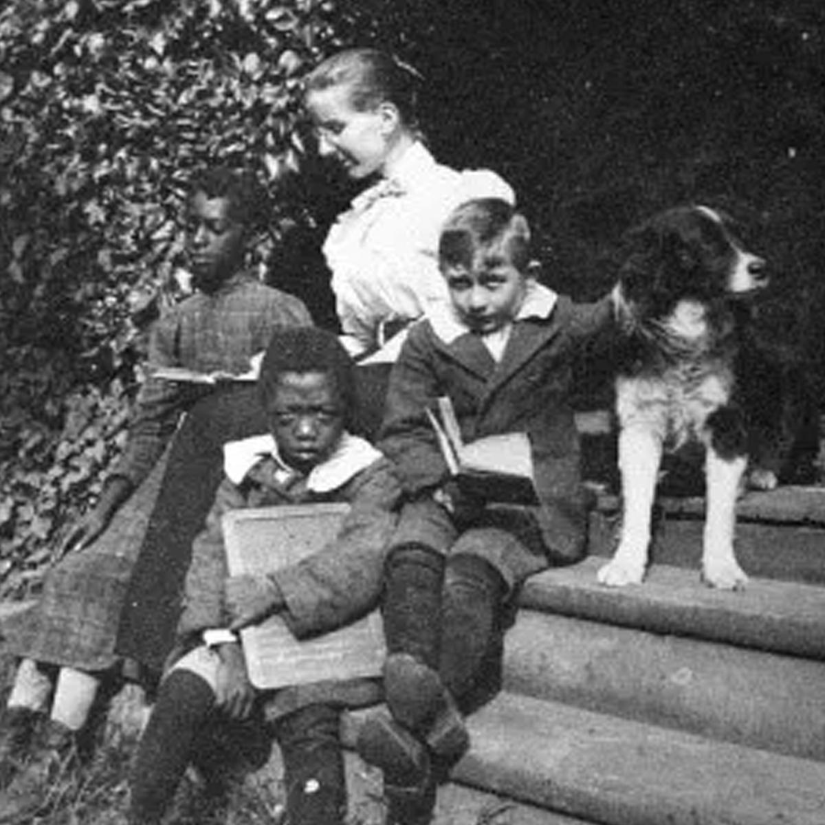 White women, Margie, teaching on stairs outside with diverse group of kids. NPS