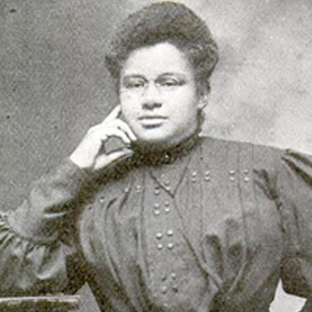 African American women, named Ida, with her left hand on her chin, and her right hand on her hip