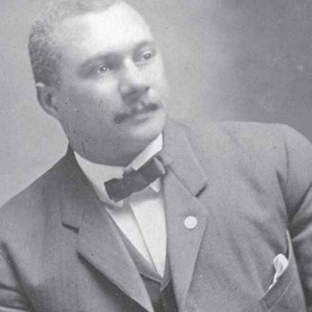 A photo of an African American man, Harry, leaning to the left, with a bowtie on. A formal photo.