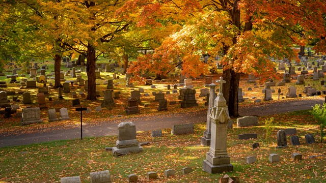 A cemetery in fall, with orange leaves everywhere.