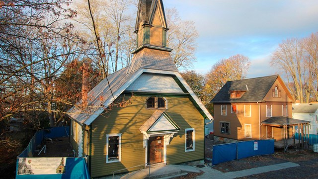 Street view of the front of the church and parsonage in autumn with construction work visible.