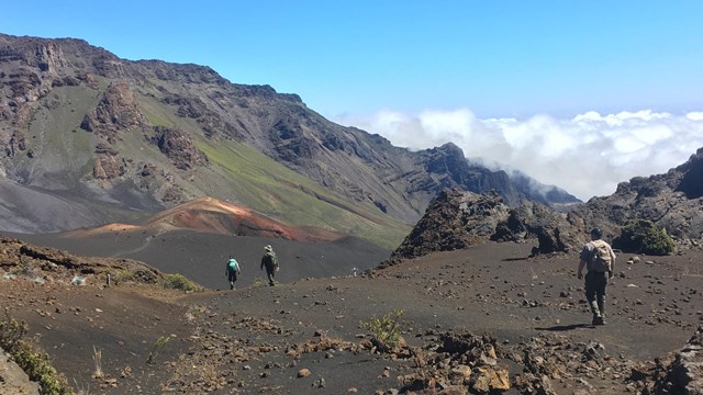 People walking through a large volcanic crater. 