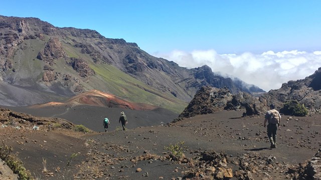 People walking through a large volcanic crater. 