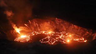 Erupting volcanic crater glowing at night