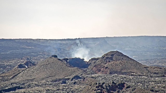 A volcanic cinder cone emitting steam. 
