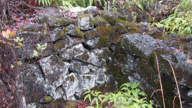 Stone wall with a wooden sign on a post