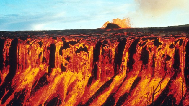 Molten lava cascades into a crater
