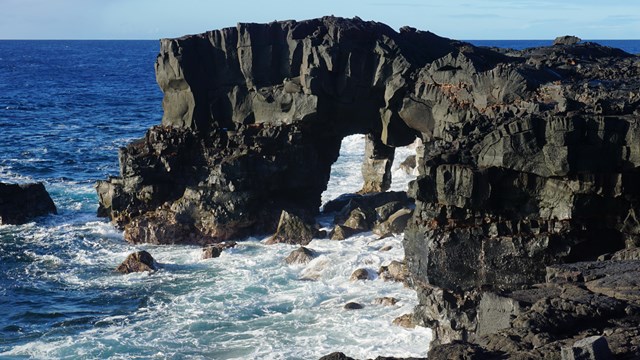 A sea arch and coastal cliffs with rough surf