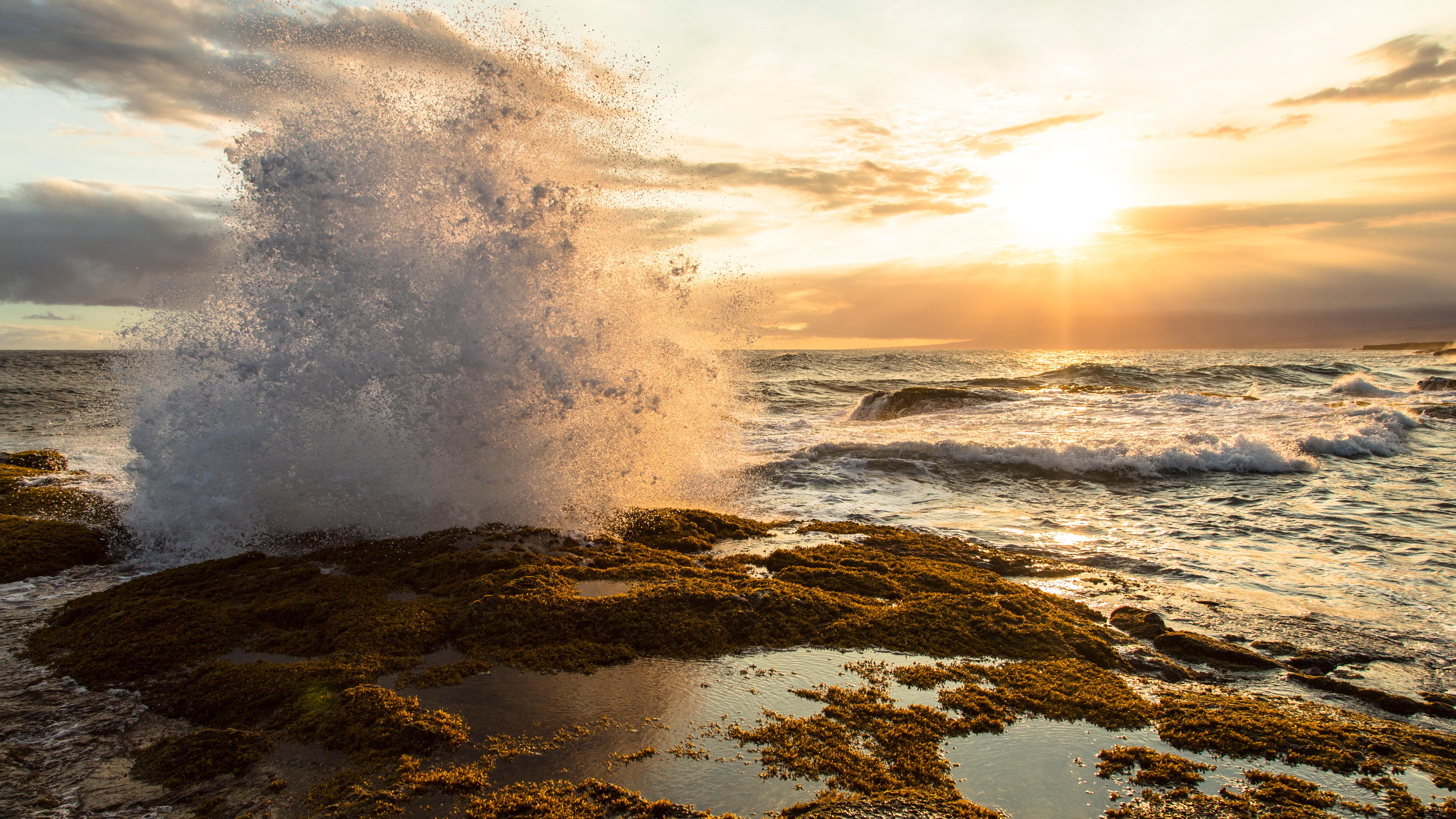 Waves crashing on rocks near tidal pools at sunset