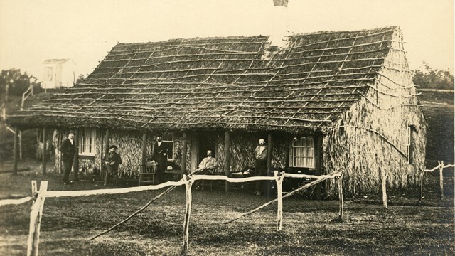 Historic photo of a small building with a thatched roof