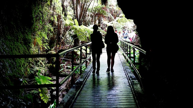 Silhouetted human figures at the entrance to a lava tube