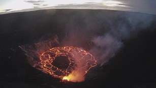 Web cam image of an erupting volcanic crater, with pooling lava in the bottom