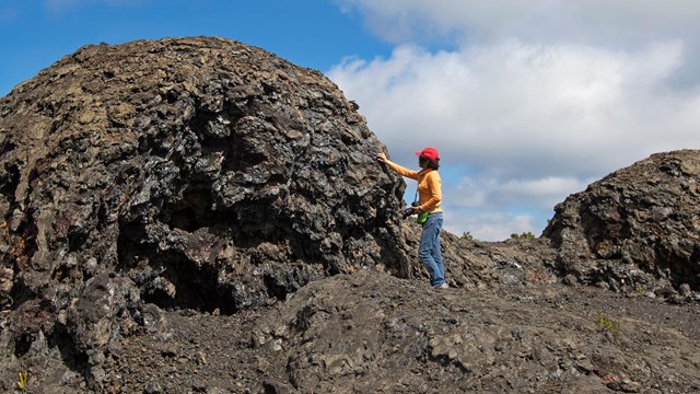 A person standing next to a large lava formation