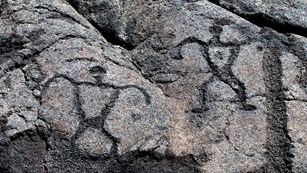 Petroglyphs of two human figures in gray rock