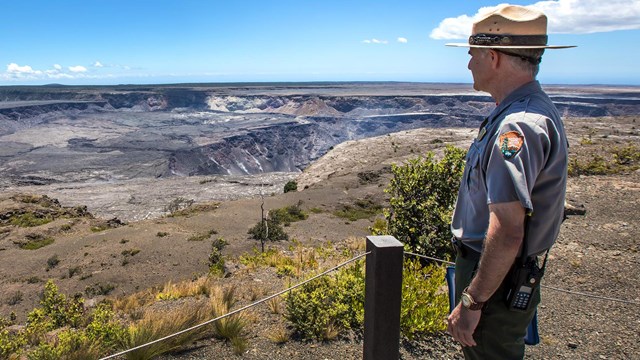 A park ranger looking toward a volcanic caldera on a sunny day