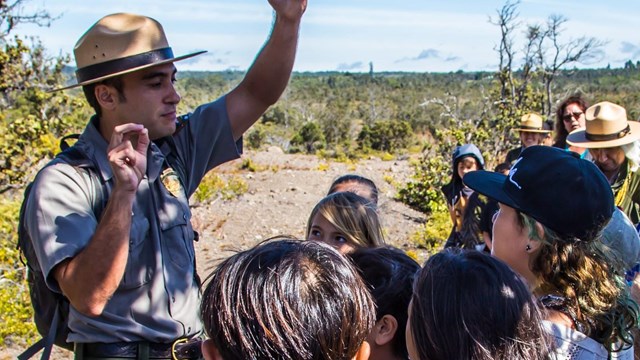 A park ranger outside with a group of children.