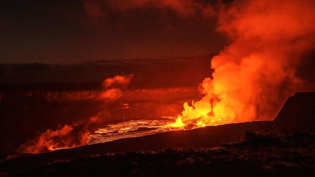 A lava lake filling a volcanic crater at night.