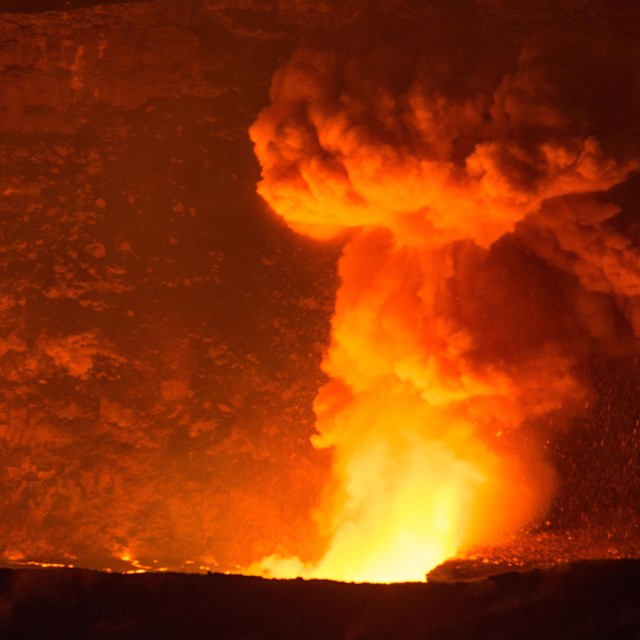 A bright red plume of smoke rises from the earth. 
