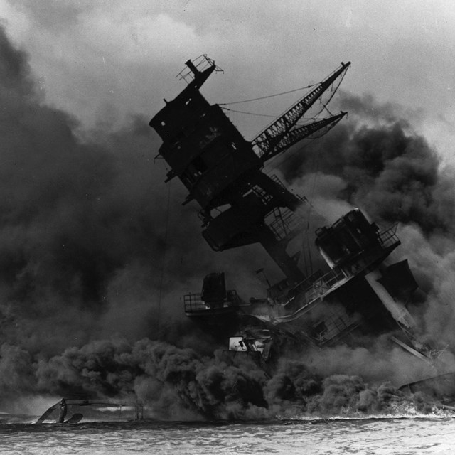 B&W photo of a WWII ship sinking and surrounded in smoke