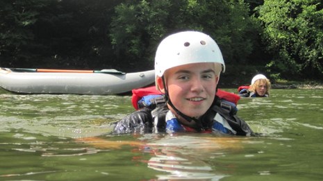 Boy swimming in river with life jacket