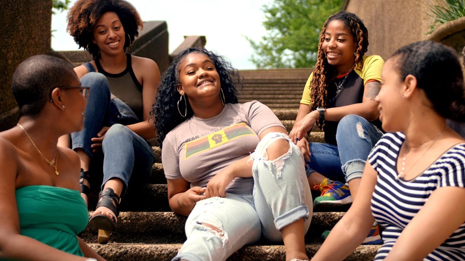 visitors enjoy conversation while sitting on steps in park