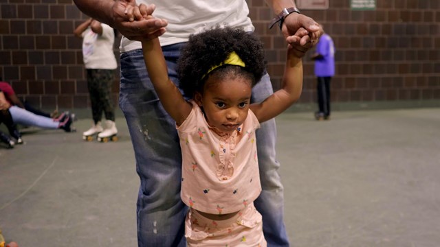 young girl skates with dad at Anacostia Park