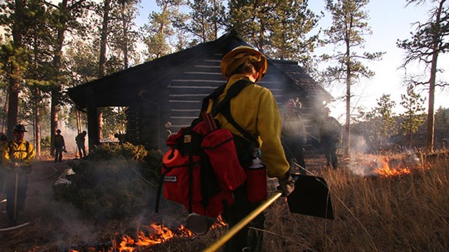 Fireman walking near burning cabin