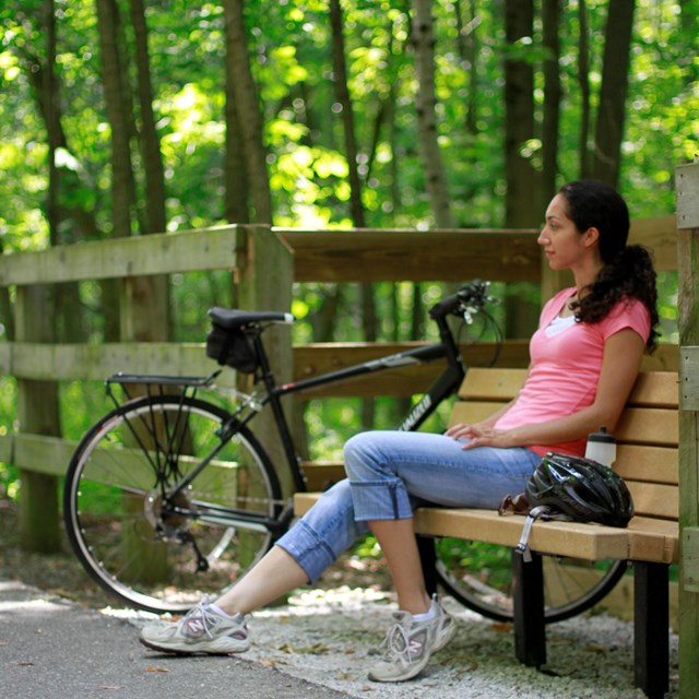 Woman sitting on park bench with bike