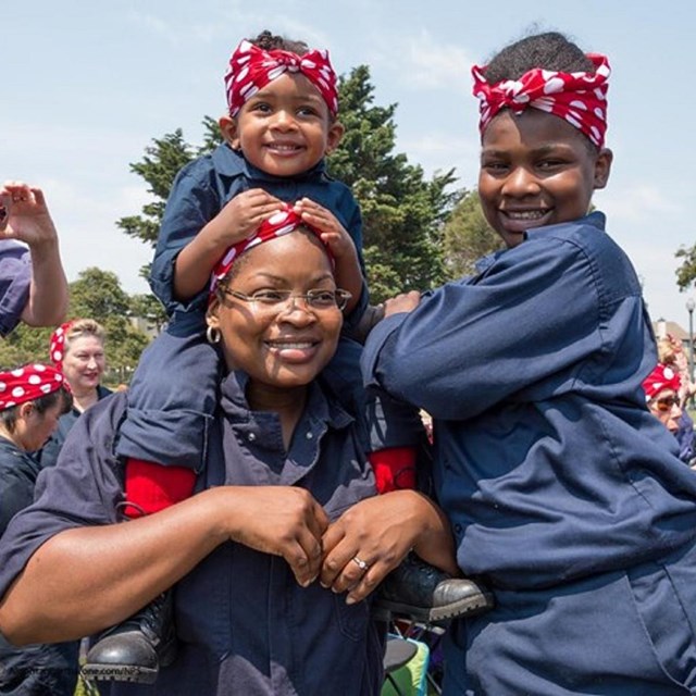 Women and children dressed as 'Rosie the Riveter' with red polka-dot bandannas 