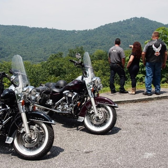 Three motorcyclists pulled over at a viewing spot enjoying the view. 
