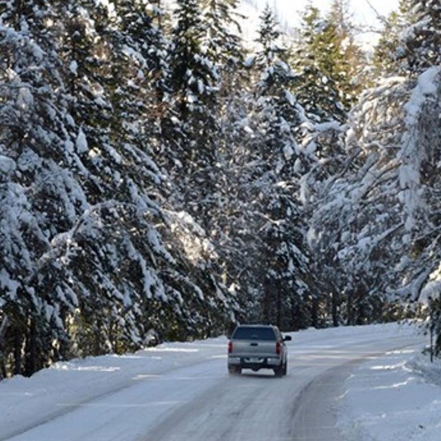 Car driving on a snow covered road in Glacier National Park