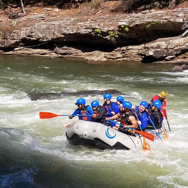 Raft on water with kids wearing life jackets and helmets