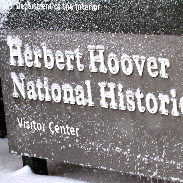 Snow collects on the raised letters of a sign for Herbert Hoover National Historic Site.