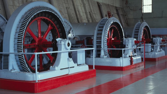 Red and white generators inside hydroelectric powerhouse