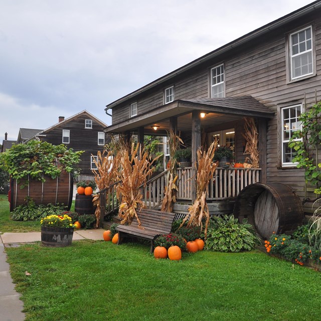 Wood house with corn and pumpkins out front. Photo by Chanilim714, CC BY-SA 3.0, 