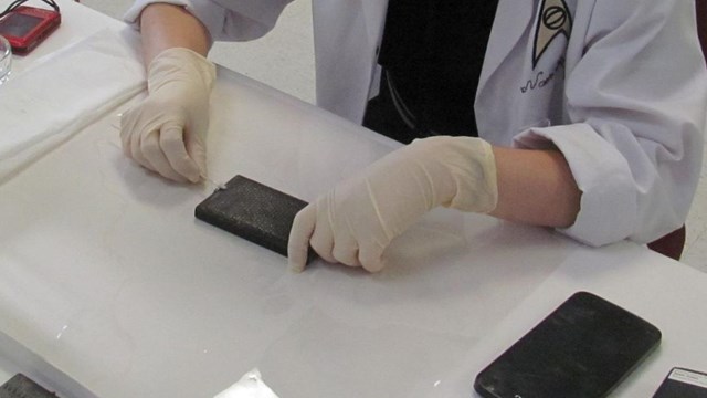 A woman in a white lab coat cleans a museum object