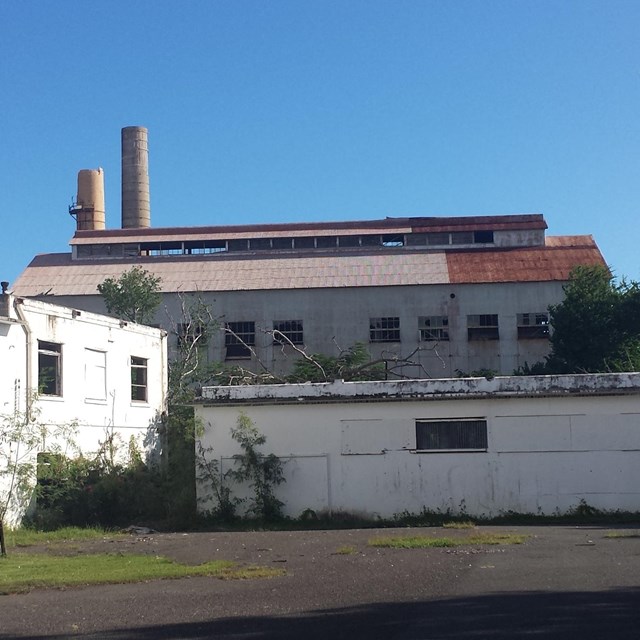 Exterior of a corrugated metal building with missing windows.