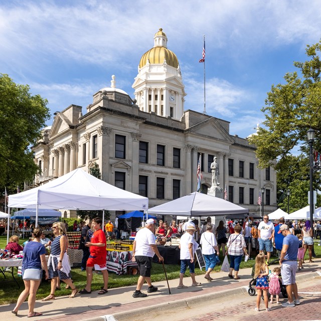 Seward, NE - background of blue cloudy sky with large gold-domed building and people in the street