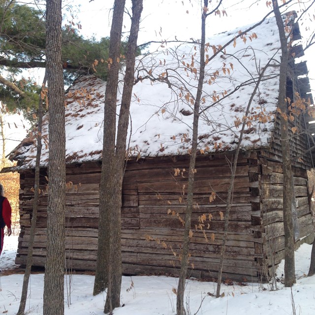 Wooden cabin with light snow on roof and ground