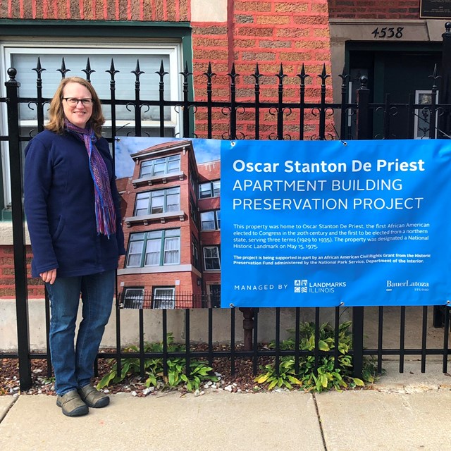 Brick building background with metal fence. Man and woman foreground surrounding blue banner.