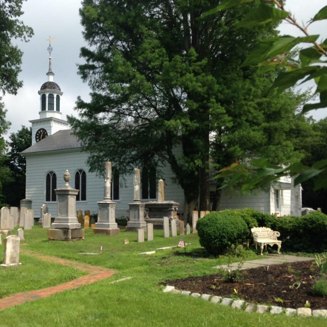 Exterior picture of white frame church and graveyard