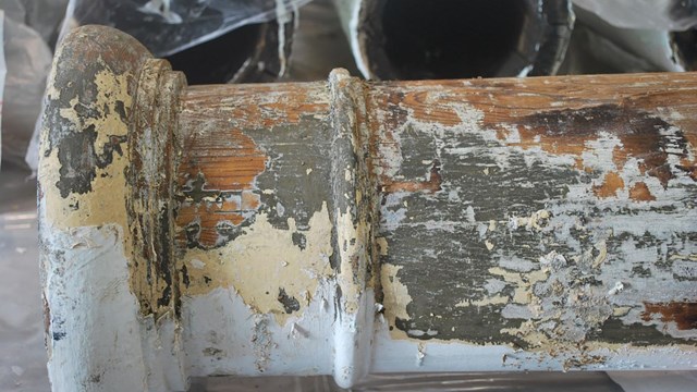 Pealing yellow, gray, and white paint expose a wood column.