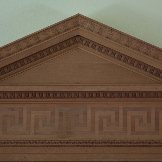An architectural pediment and frieze in red stone